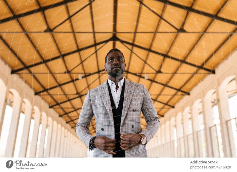 Stylish black businessman in wristwatch under building ceiling well dressed style masculine gentleman executive macho jacket ornament accessory contemporary