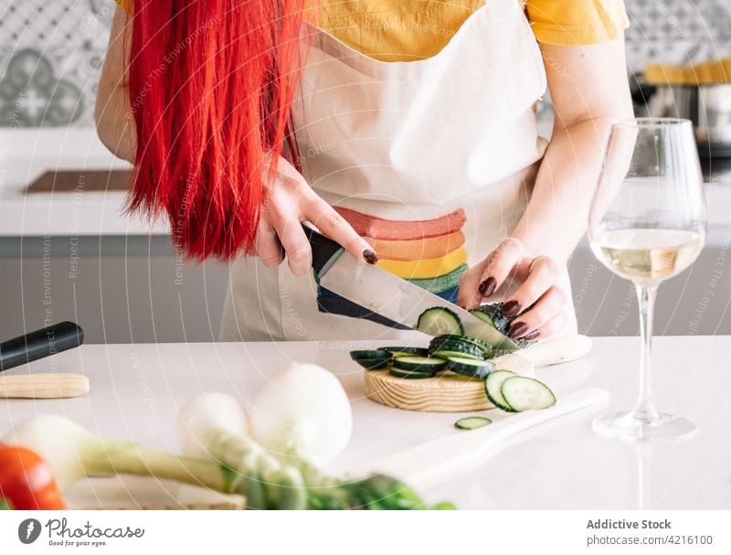 Crop lesbian woman cutting cucumber while preparing lunch at home healthy food culinary recipe vegetable wine kitchen knife onion green cutting board process