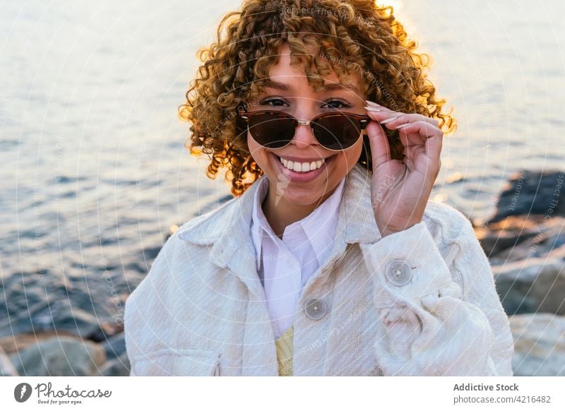 Black woman enjoying freedom at seaside seashore sunset arm cheerful female ethnic black african american sunglasses summer holiday nature smile evening