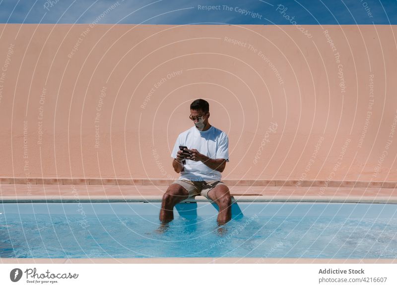 Male freelancer talking on smartphone at poolside man speak telework summer distance male device gadget conversation remote connection online call internet guy