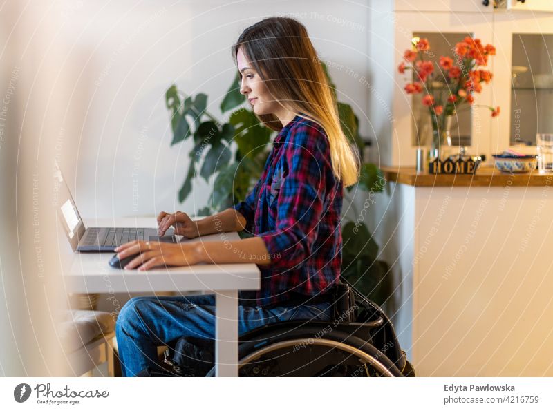 Woman in wheelchair using laptop at home domestic life disability disabled confidence woman independent indoors house people young adult casual female Caucasian