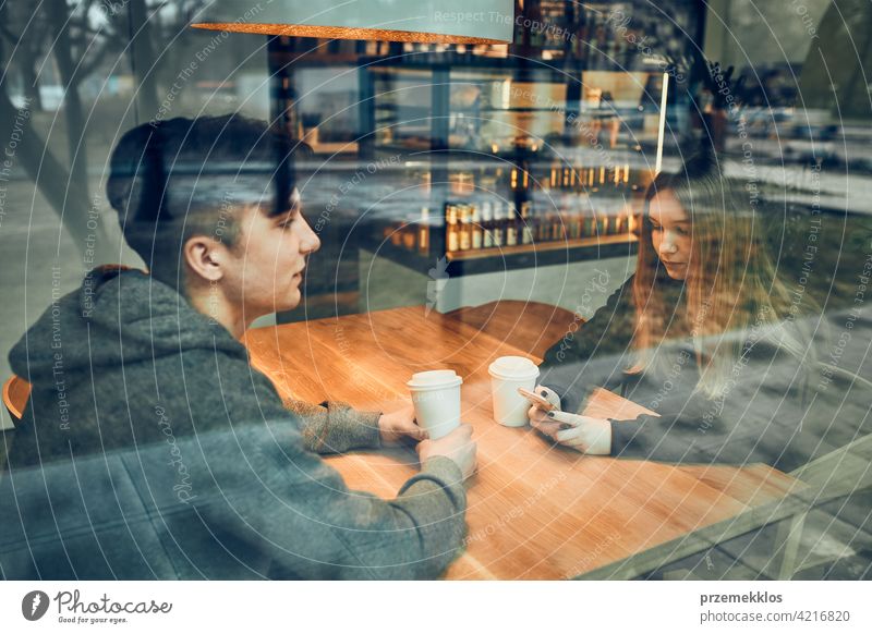 Friends having a chat, talking together, drinking coffee, sitting in a cafe. Young man and woman relaxing in cafe, having a break buy person restaurant