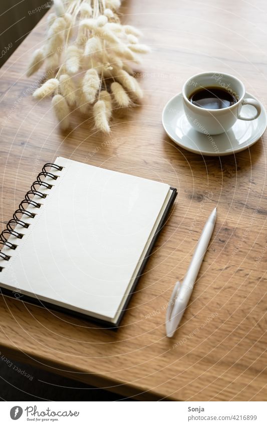 An empty notepad, a ballpoint pen and a cup of coffee on a wooden table Notebook Coffee Ballpoint pen at home Wooden table Paper Tabletop Feminine Cup Diary