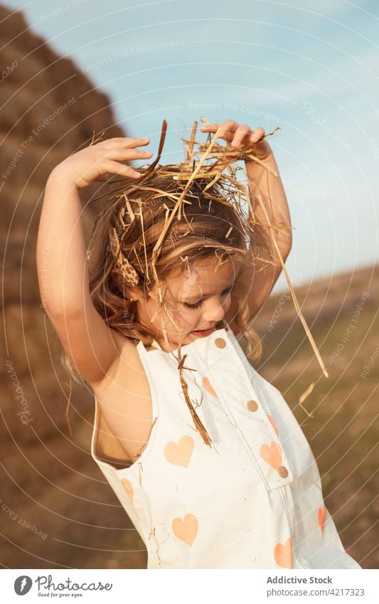 Cute girl playing with straw in field bale hay having fun countryside cheerful child childhood cute adorable kid nature overall idyllic little happy joy rural