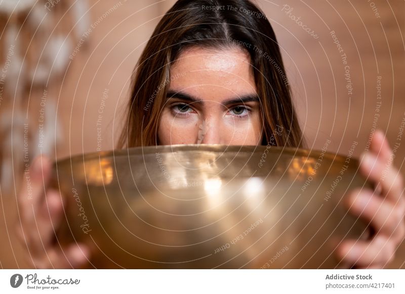 Crop woman with bowl gong during spiritual practice cover mouth prayer vitality energy oriental portrait harmony tibetan asian culture tradition himalayan