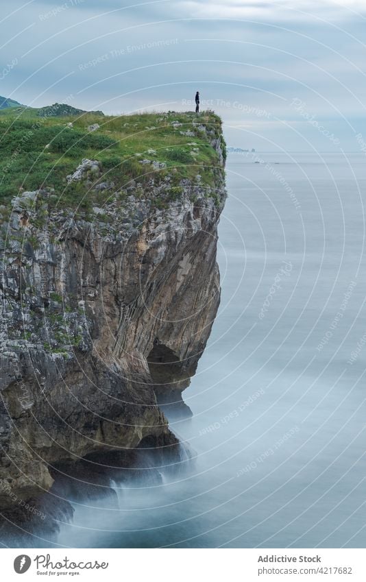 Person standing on cliff over sea person rocky edge silhouette cloudy shore freedom asturias spain ribadesella coast sky seaside traveler water seascape