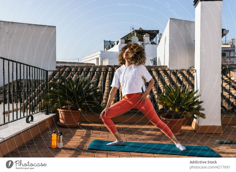 Black woman doing yoga in Warrior pose on rooftop warrior pose practice training asana balance relax female ethnic black african american harmony calm