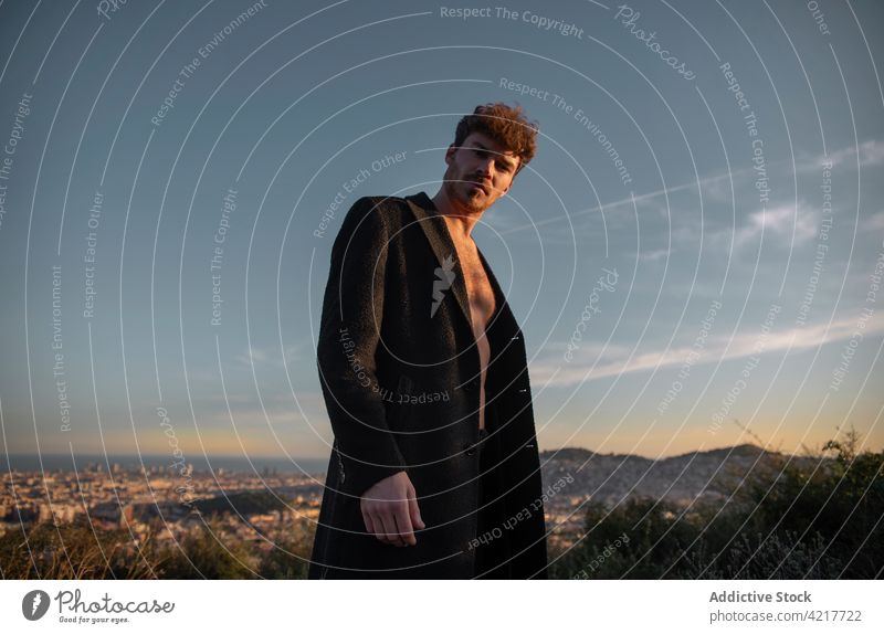 Stylish man on grass against ridges in evening style confident cool masculine macho individuality sky portrait virile cloudy highland sunset brutal self assured