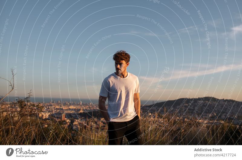 Stylish man on grass against ridges in evening style confident cool masculine macho individuality sky portrait virile cloudy highland sunset brutal self assured