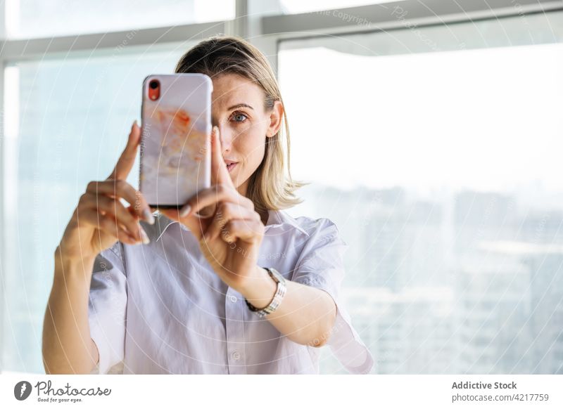 Woman taking selfie in office on smartphone woman blond portrait photo mobile casual caucasian city cityscape self portrait memory copy space device building