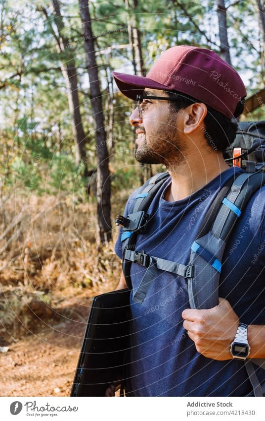 Hiker with backpack walking through green trees in forest man nomad backpacker trekking adventure explore discover hike travel nature male hiker tourist