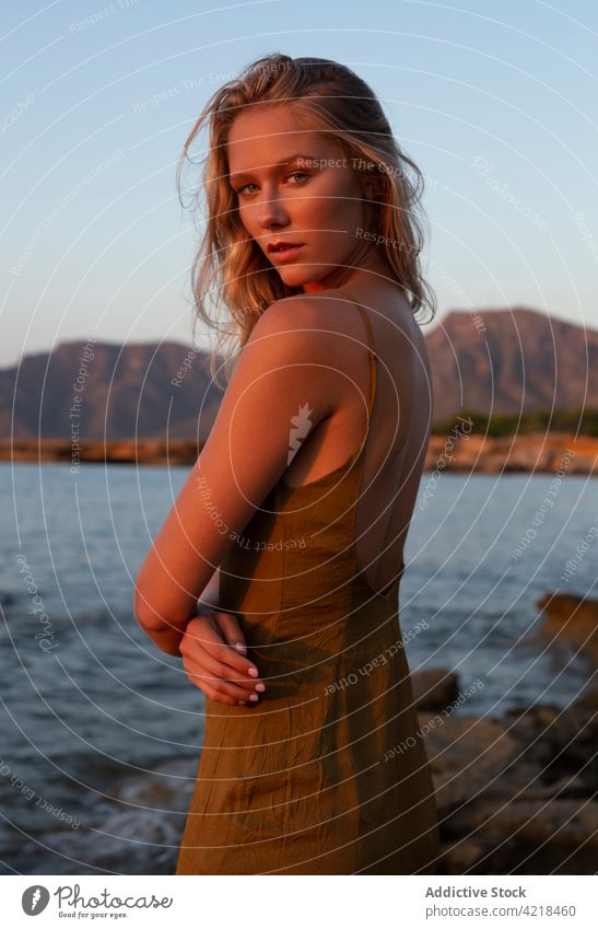 Peaceful female standing on rocky coast in evening woman shore sea nature environment sunset holiday carefree harmony peaceful vacation wave sundown seashore