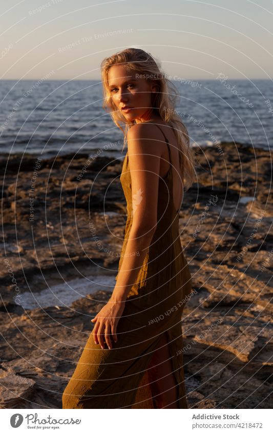 Peaceful female standing on rocky coast in evening woman shore sea nature environment sunset holiday carefree harmony peaceful vacation wave sundown seashore