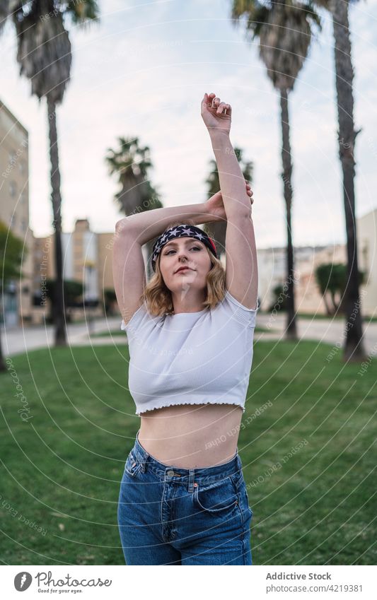 Carefree American woman standing in city park bandana carefree palm tropical summer lawn enjoy female american smile content style urban trendy happy glad