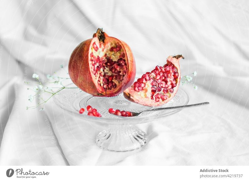 Delicious cut pomegranate on stand with spoon fruit seed natural vitamin fresh sprig fabric crumpled flower organic delicious ripe aroma yummy bloom bright