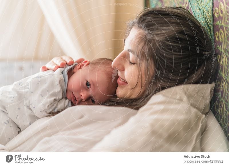 Mother cuddling newborn baby on bed mom embrace babyhood motherhood harmony woman nap serene house parenthood together soft happy smile asleep calm bedroom