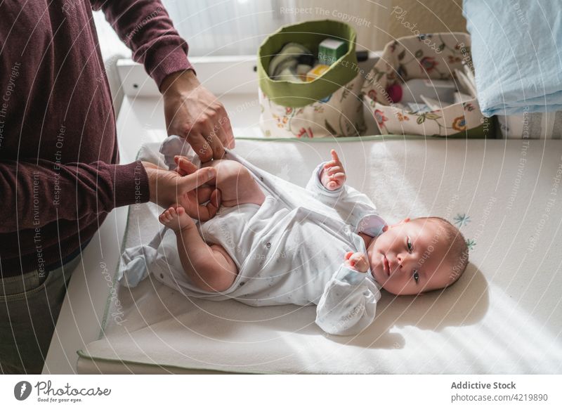 Crop dad dressing cute baby on table in house father infant newborn babyhood fatherhood spend time charming man idyllic innocent diaper home together parent