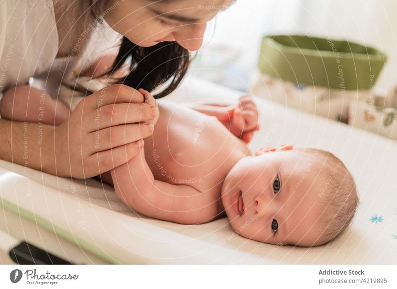 Crop mother changing diaper of newborn baby at home mom put on infant charming sweet table woman change motherhood babyhood parenthood idyllic innocent harmony