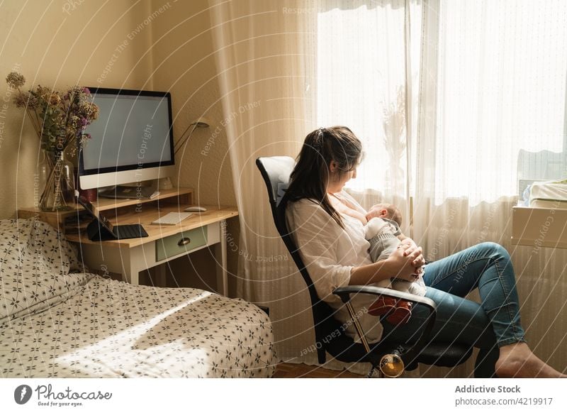 Mother breastfeeding newborn baby in armchair at home mother embrace motherhood babyhood harmony woman idyllic mom innocent house tender curtain suckle serene