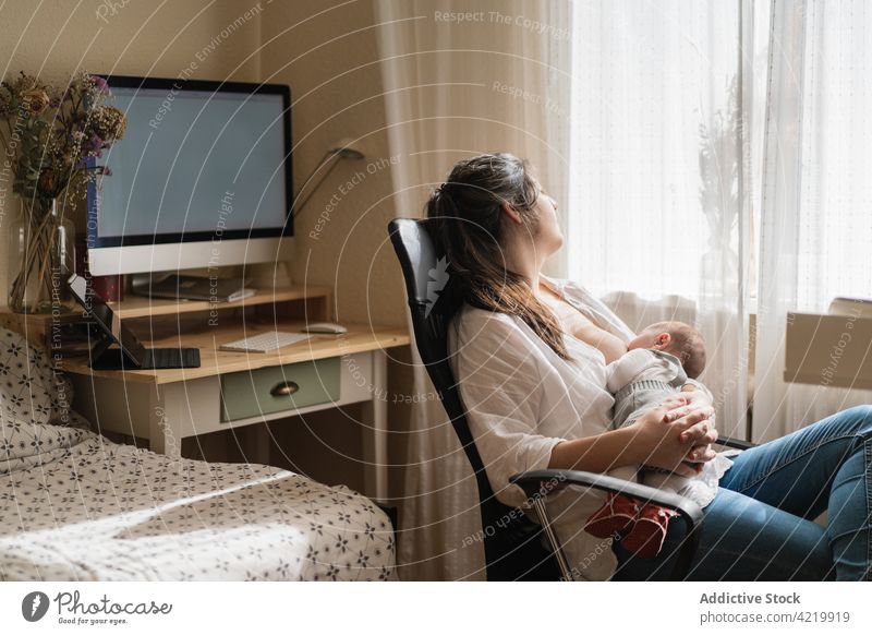 Mother breastfeeding newborn baby in armchair at home mother embrace motherhood babyhood harmony woman idyllic mom innocent house tender curtain suckle serene