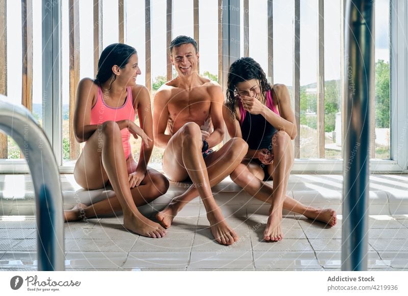 Smiling swimmers resting on floor after training smile legs crossed break body wellness fit professional together sportspeople women man group partner content