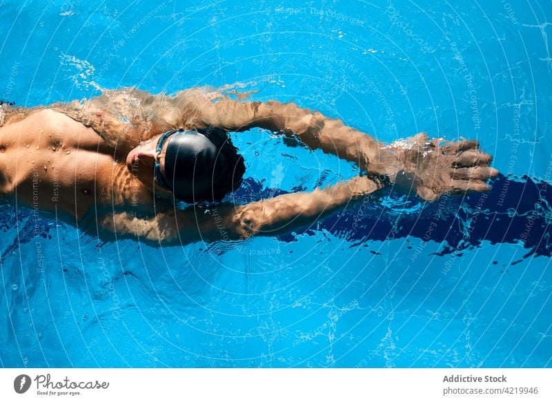 Sportsman in goggles swimming in pool during workout swimmer sport arms raised training exercise practice motivation energy strength masculine wellness fit