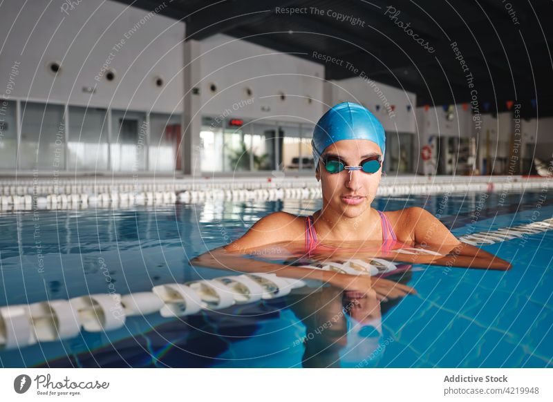 Swimmer in swimsuit in pool during break from workout swimmer sport training wellness contemplate woman portrait professional lane line floating marker dreamy