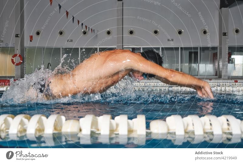 Sportsman in goggles swimming in pool during training swimmer butterfly stroke sport workout fast strong motion motivation power energy splash practice exercise