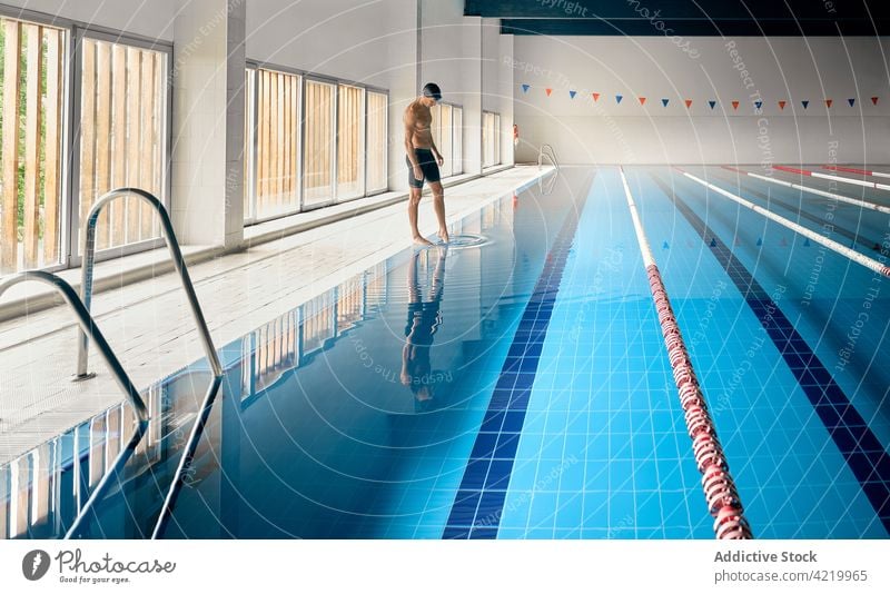 Swimmer touching water while reflecting in pool swimmer reflection sport workout training professional wellness lane man naked torso vitality body sportsman