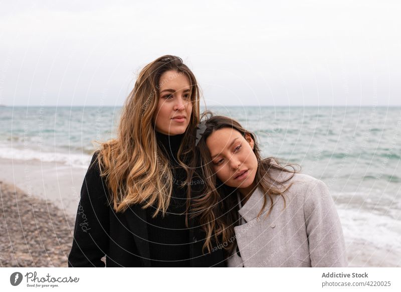 Tender couple of women standing on seashore in autumn lesbian relationship love girlfriend seaside female lgbt together homosexual ocean water bonding beach