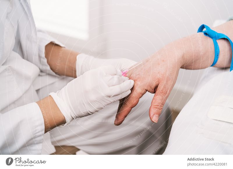 Crop nurse preparing patient for intravenous drip in clinic medical procedure prepare health care tourniquet uniform hospital professional glove sterile