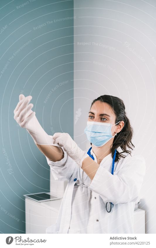 Physician putting on latex glove at work in clinic physician put on professional medical uniform protect sterile woman hospital nurse health care prevent mask