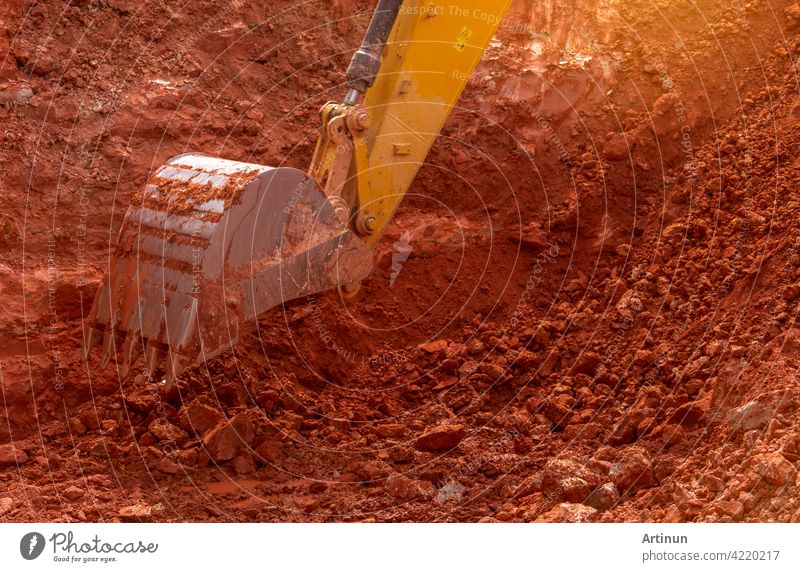 Backhoe working by digging soil at construction site. Bucket of backhoe digging soil. Crawler excavator digging on dirt. Closeup backhoe bucket of yellow backhoe. Earthmoving. Trenching machine.