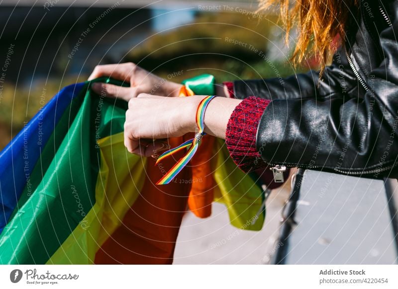 Crop woman with LGBT flag and in rainbow bracelet lesbian lgbt homosexual city lgbtq symbol female proud freedom pride liberty gay urban right equal content