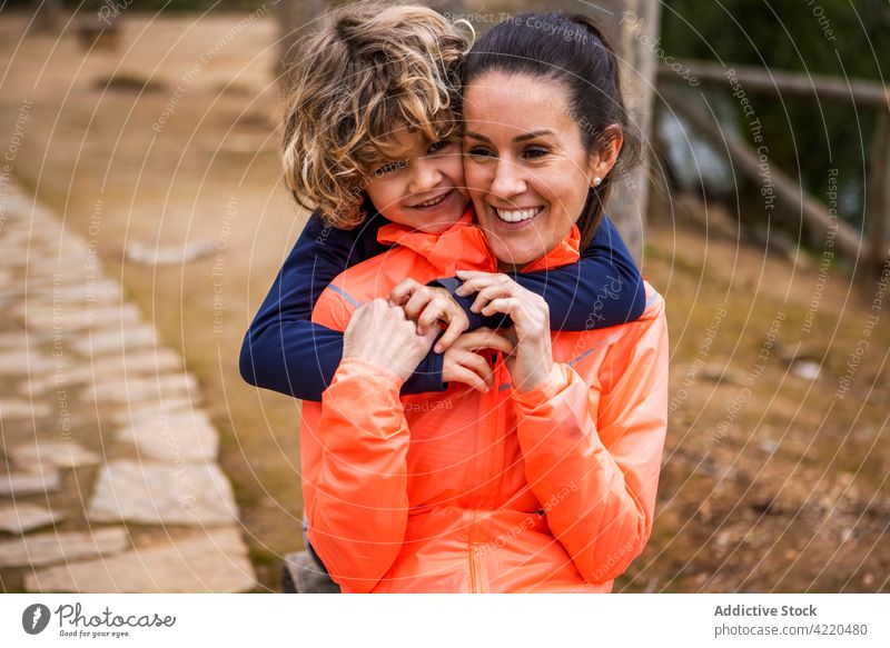 Son embracing mom sitting on bench in park son embrace childhood smile motherhood interact idyllic portrait woman content boy delight happy enjoy glad admire