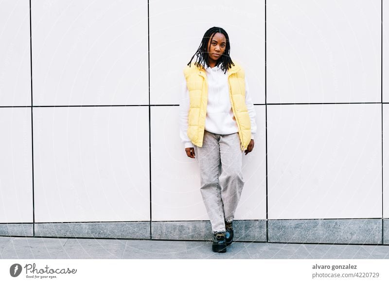 Woman leaning on street wall. che portrait woman african american urban black outdoors standing style city braids hairstyle clothing afro trendy one posing