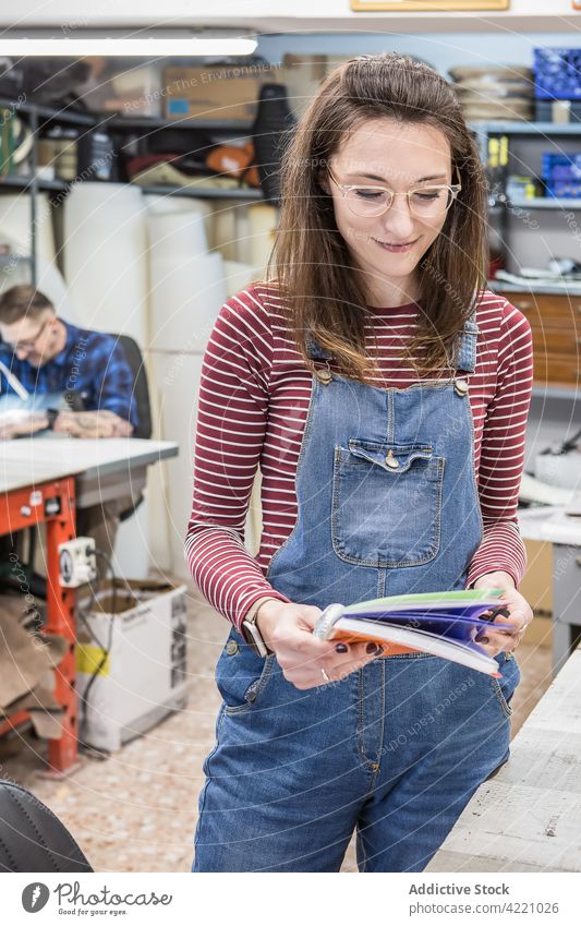 Smiling craftswoman with notebook in workshop notepad studio smile artisan planner creative female craftsmanship handicraft handmade upholstery workplace hobby