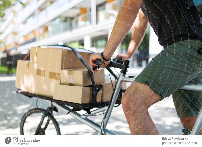 Bike courier making a delivery people young adult man male smiling happy blue collar Courier dispatch rider delivery man delivering package packages boxes