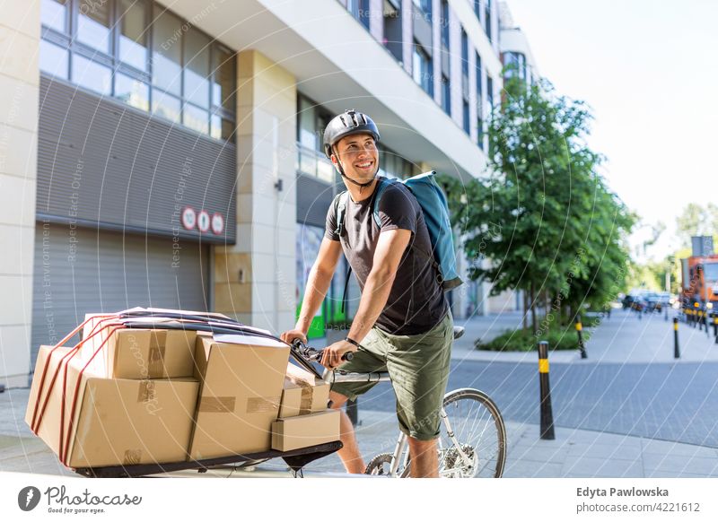 Bicycle messenger making a delivery on a cargo bike people young adult man male smiling happy blue collar Courier dispatch rider delivery man delivering package