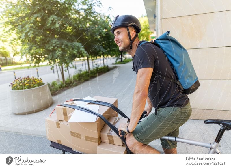 Bicycle messenger making a delivery on a cargo bike people young adult man male smiling happy blue collar Courier dispatch rider delivery man delivering package