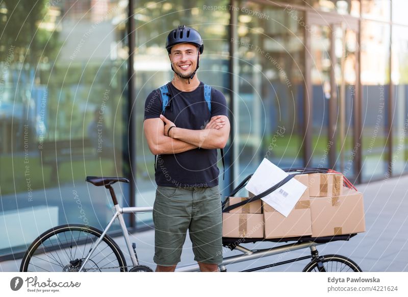 Bicycle messenger making a delivery on a cargo bike people young adult man male smiling happy blue collar Courier dispatch rider delivery man delivering package