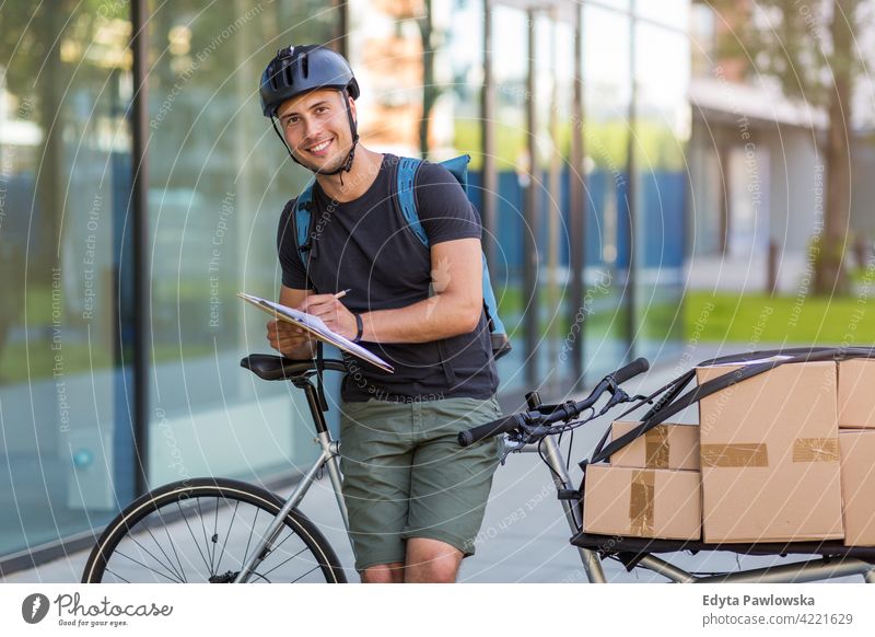 Bicycle messenger making a delivery on a cargo bike people young adult man male smiling happy blue collar Courier dispatch rider delivery man delivering package