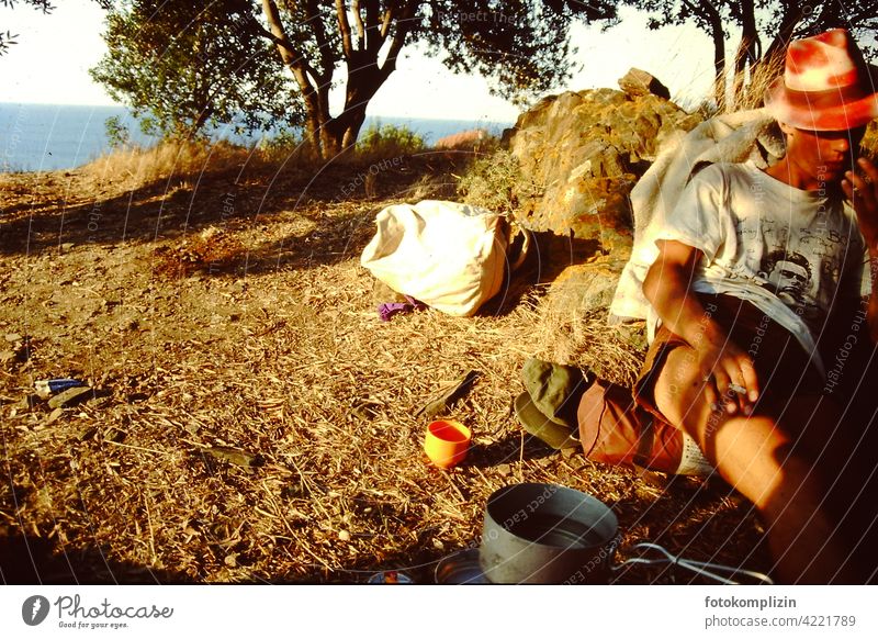 cool young man sitting on the ground in the nature and smoking globetrotters travelers simple life Traveling time-out relaxed Trip Mobile home feel free