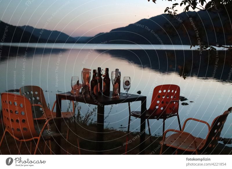 End of work or abandoned table with beer bottles and chairs at a lake at dusk Closing time after-work beer Table forsake sb./sth. Retro Lake Dusk contacts