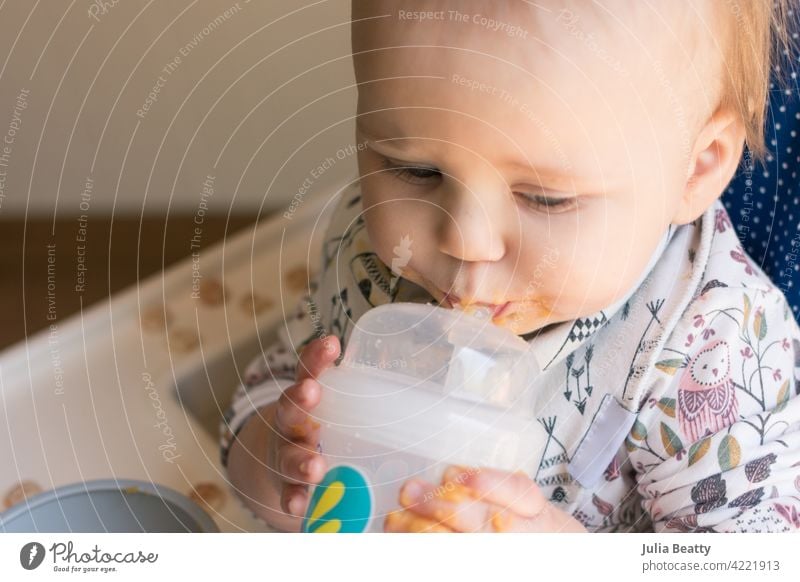 Young toddler learning to use a straw cup to drink water; promoting lip closure, cheek tightening, and tongue elevation baby led weaning training 10 months old