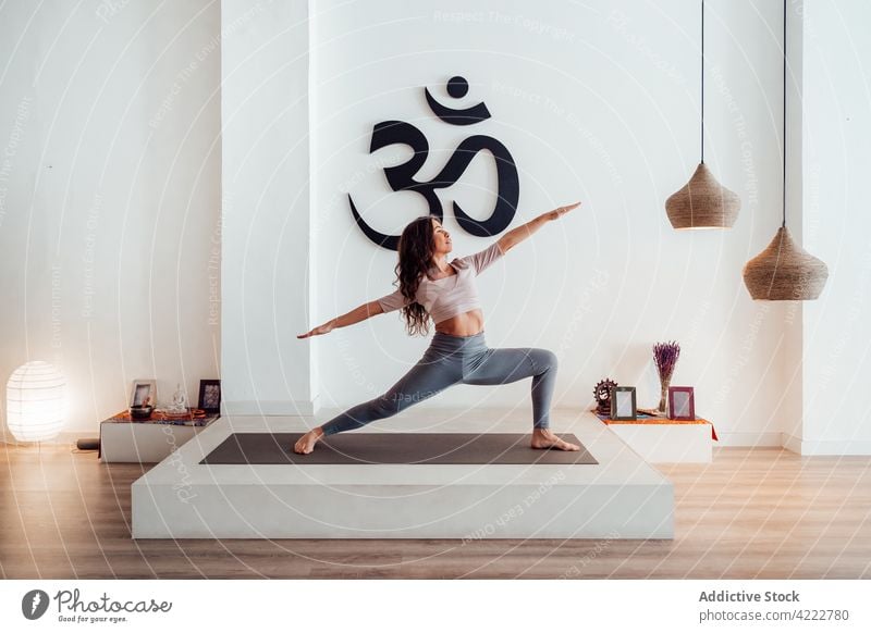 Woman doing yoga in Warrior two pose in studio woman warrior two practice grace slim flexible balance mindfulness female asana wellbeing mat vitality harmony