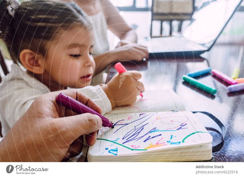 Crop mother browsing laptop and child drawing at home together childcare marker felt pen creative education kid notebook table little childhood hobby paper art