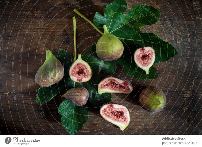 Ripe fig halves on leaves on brown background fruit ripe juicy healthy food pulp fresh vitamin natural leaf foliage vein half cut organic ingredient sweet tasty