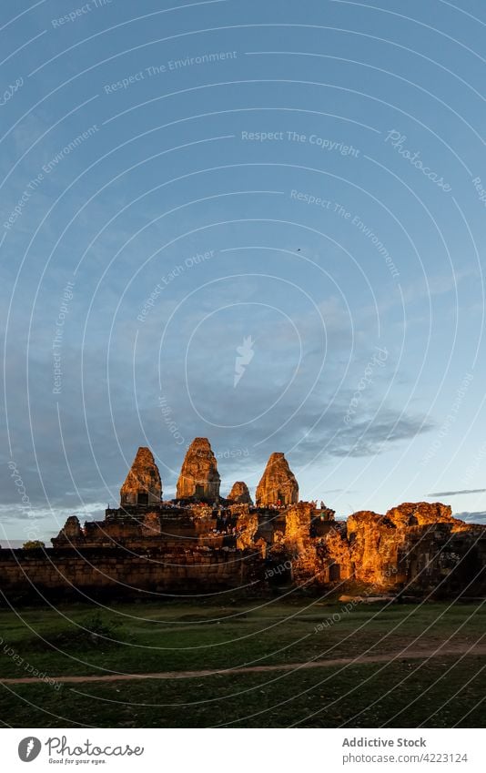 Angkor Wat with temple facade under cloudy sky in city angkor wat architecture historic heritage religion aged style complex old lawn exterior atmosphere air