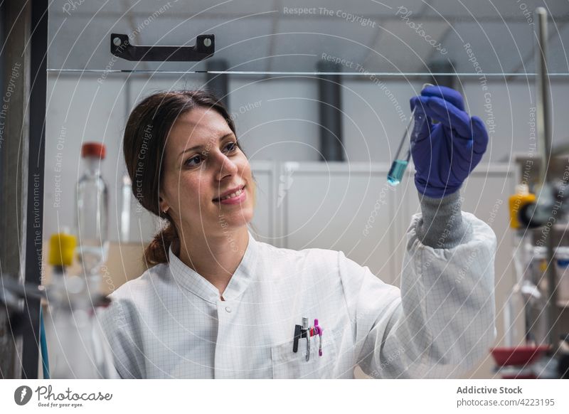 Smiling chemist looking at substance in test tube woman laboratory chemical smile cheerful scientist expert experiment science research liquid chemistry